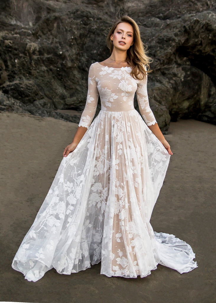 Bride wearing Ari dress on beach in front of a rock formation