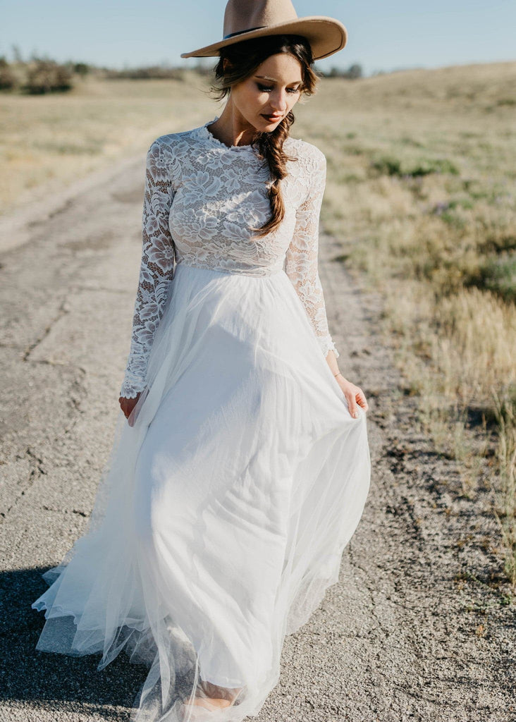 Bride in hat wearing Zoey 2.0 wedding dress walking down dirt road