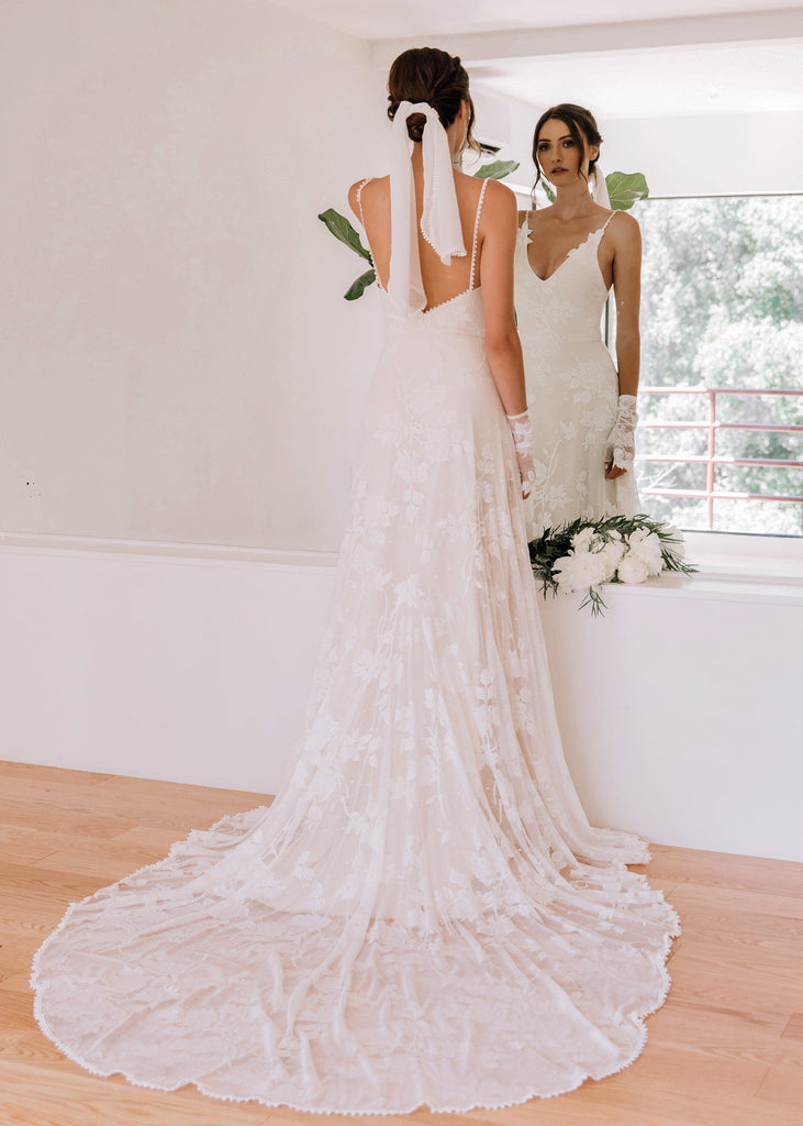 Bride wearing Lilith Dress looking at herself in mirror wall