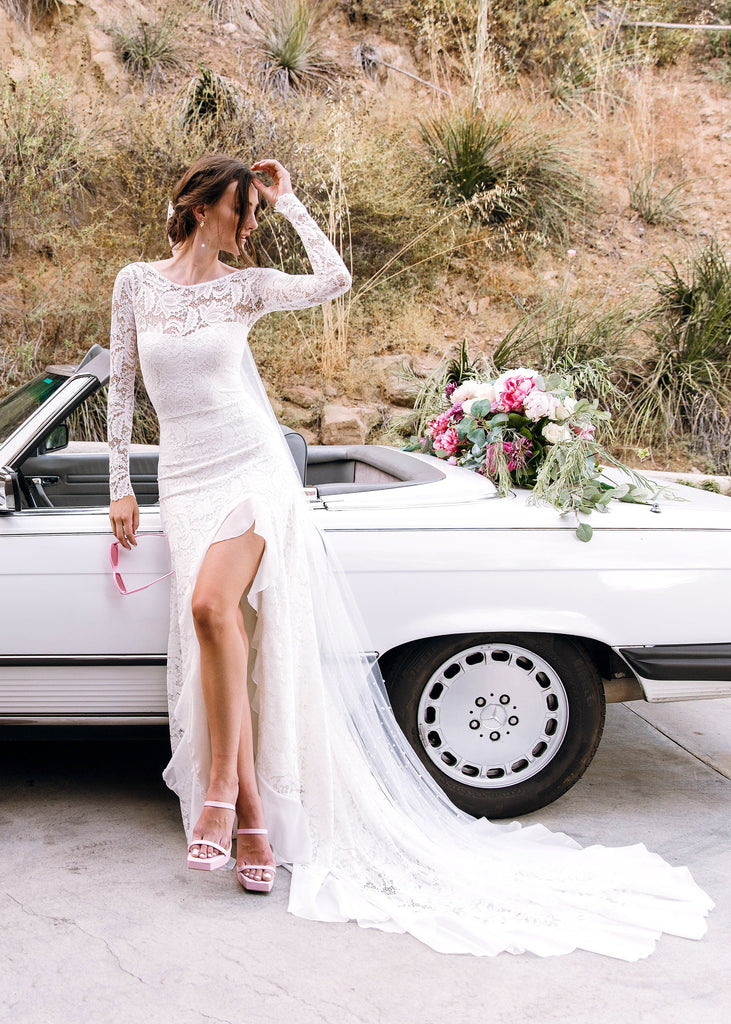 Bride wearing Sasha Dress leaning against white convertible