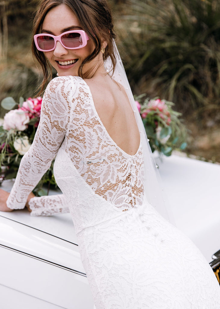 Bride in pink sunglasses wearing Sasha Dress leaning over white convertible