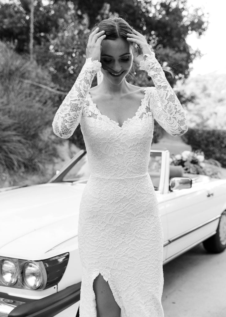 Bride wearing Sia Dress standing in front of convertible, adjusting her hair